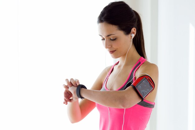 Fitness woman checking her smartwatch while taking a break during workout active.
